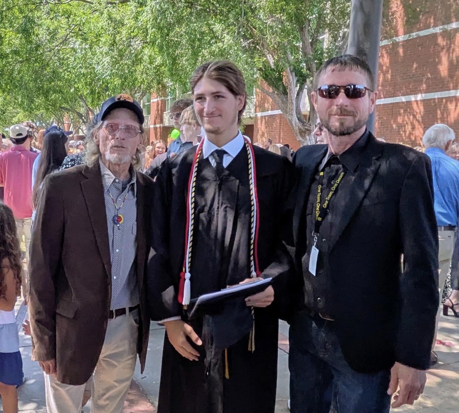 Hayden in graduation regalia with family and instructors
