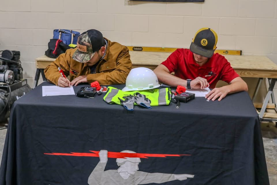 Hayden signing his MetroPower agreement at a table set with tools