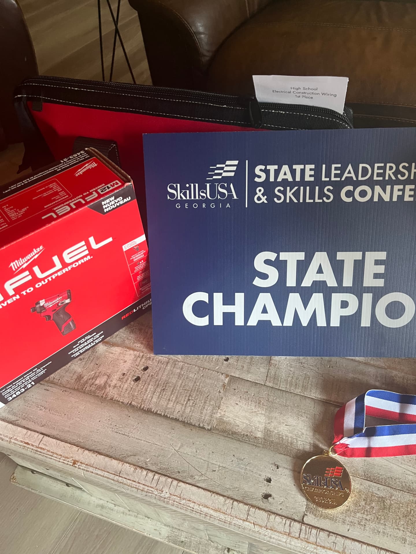 State Champion sign displayed with a gold medal and a first place Electrical Construction Wiring award