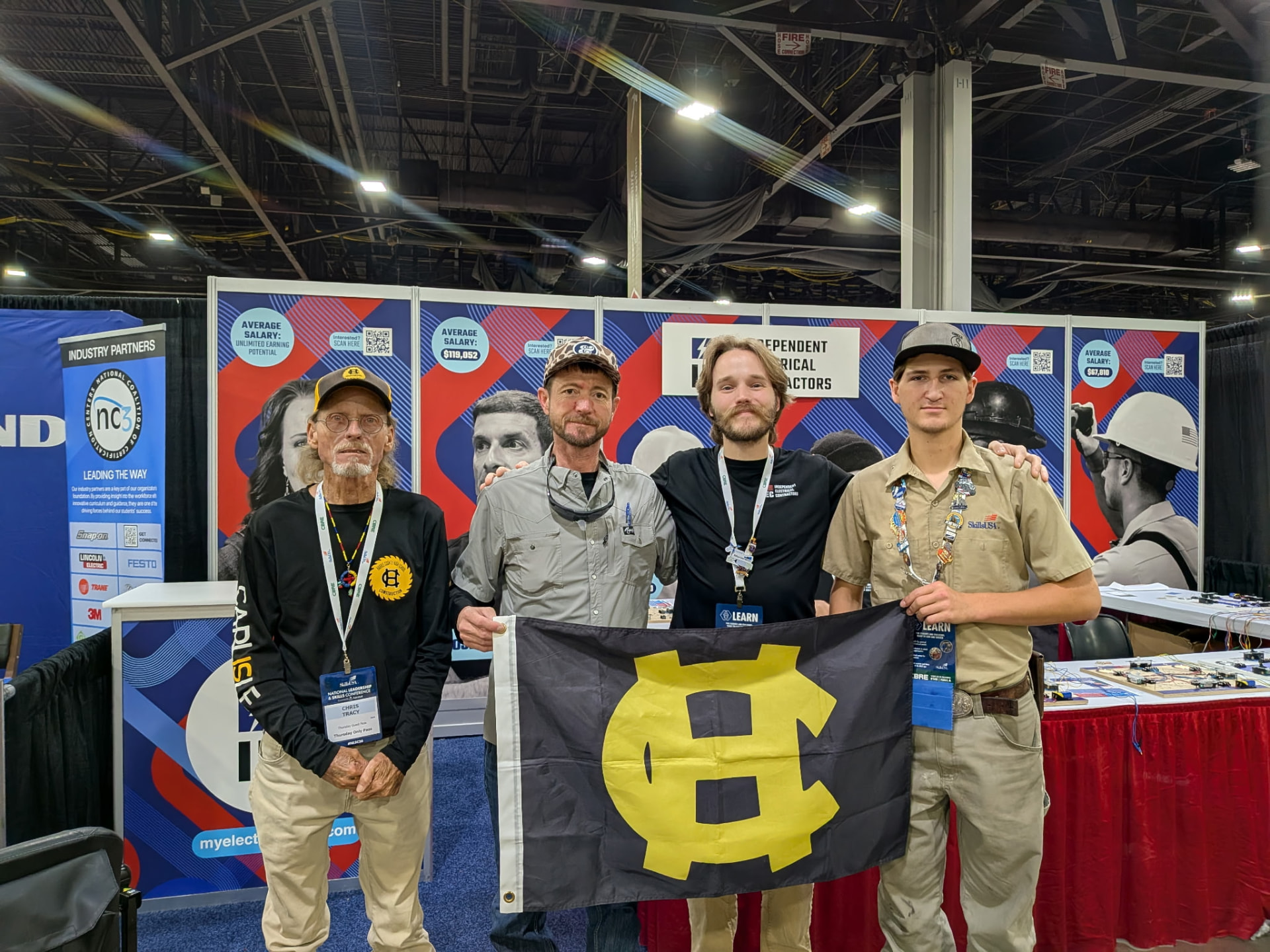 Hayden and instructors holding a Harris County flag at an industry booth during Nationals