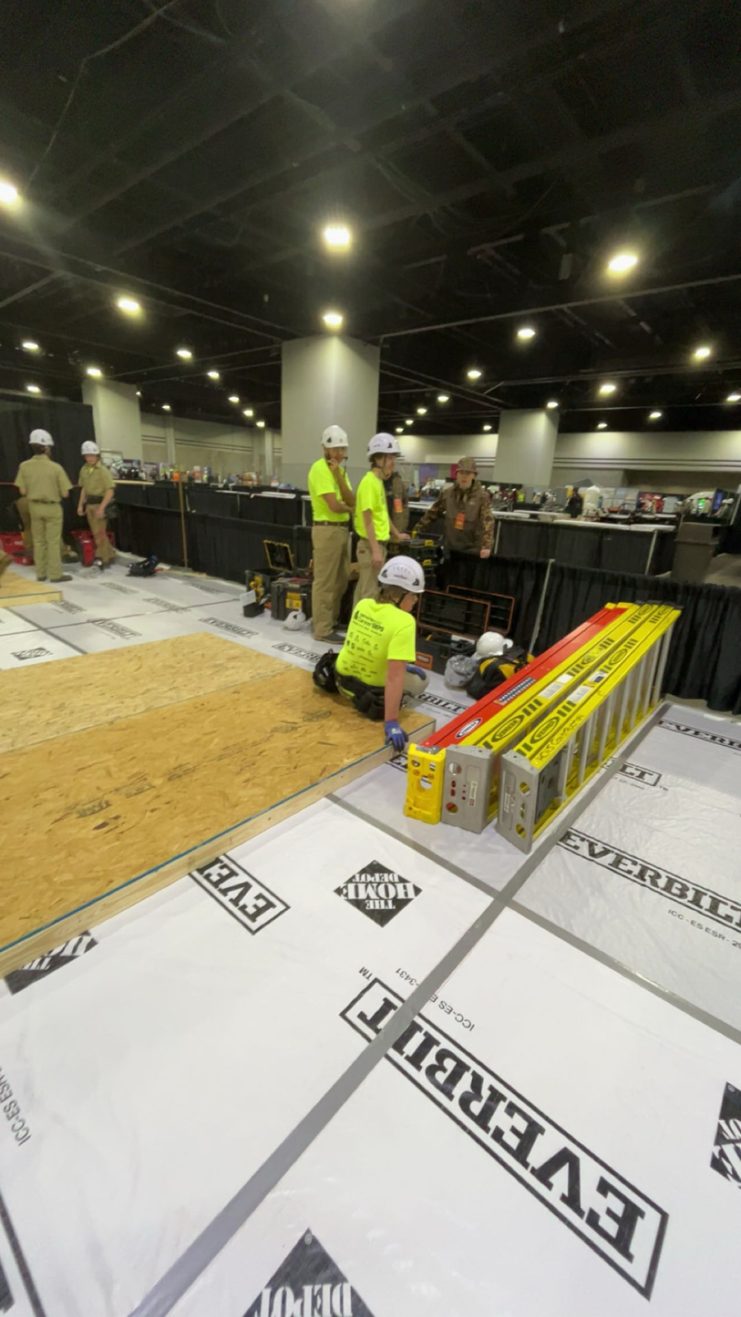 Wide view of a carpentry competition floor with students framing project walls