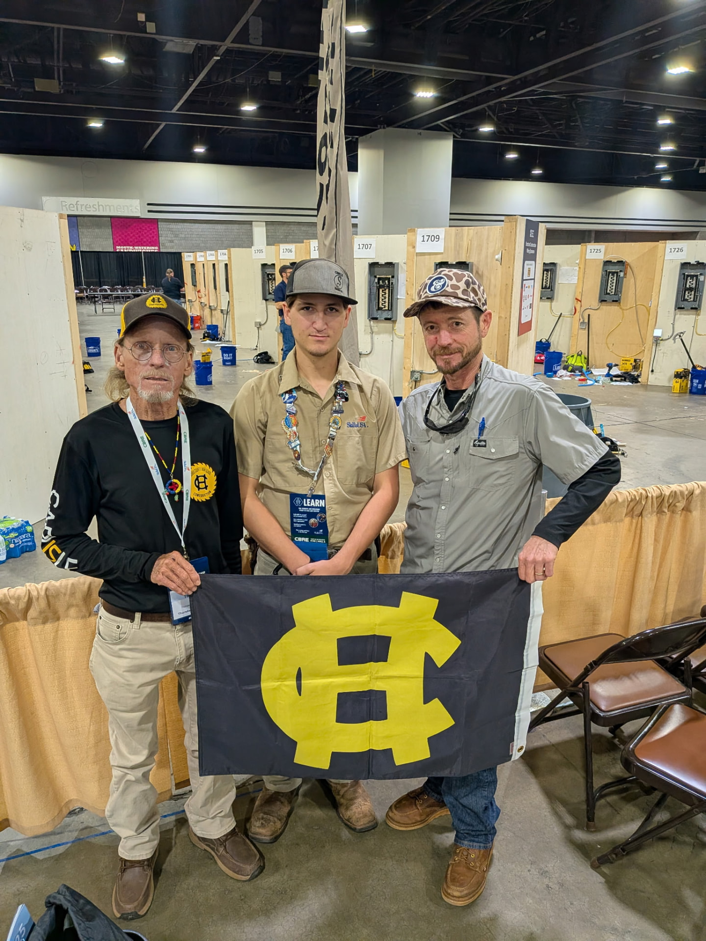 Group holding a Harris County flag in front of national competition wiring bays