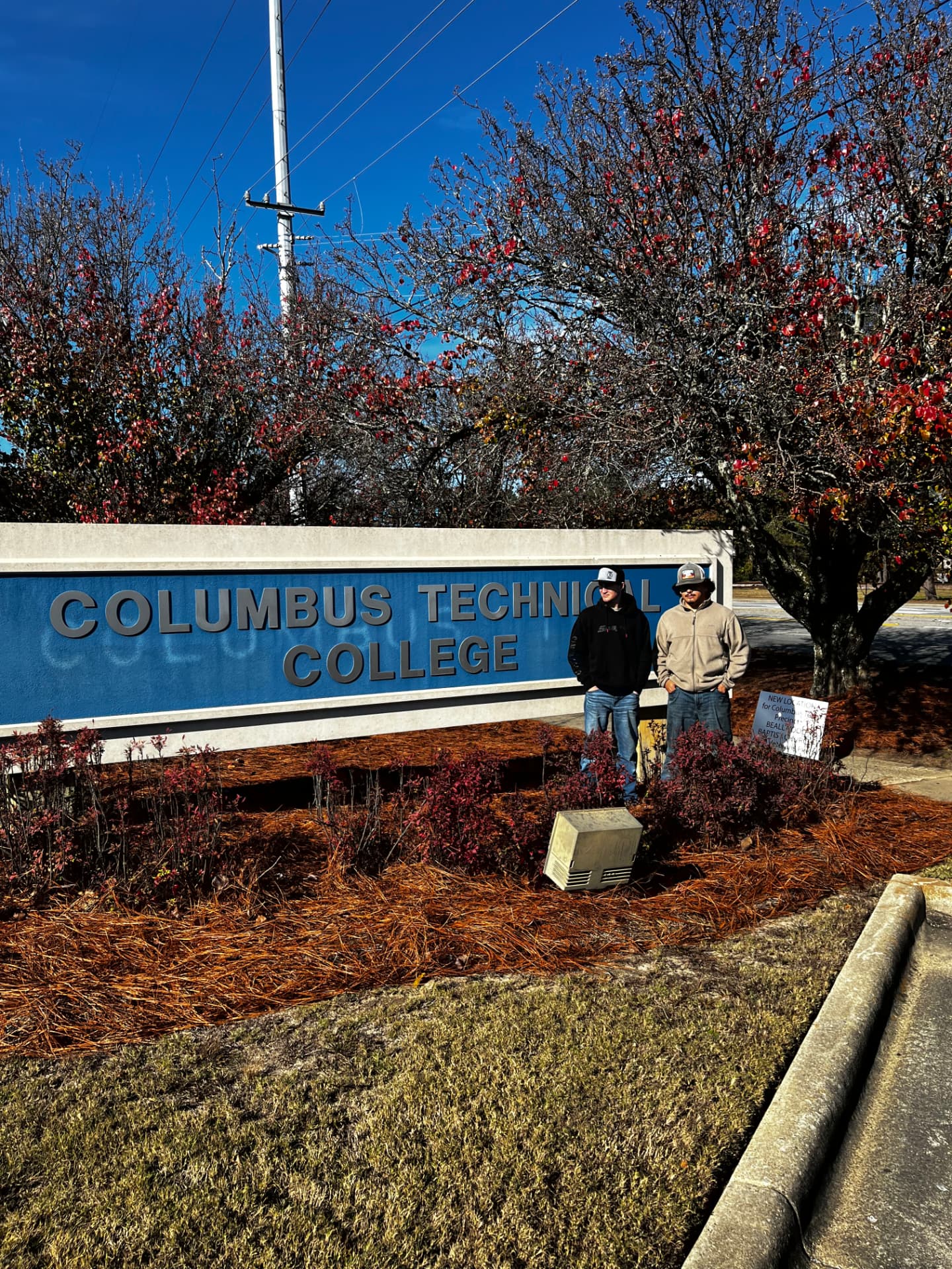 Hayden and a fellow member standing by the Columbus Technical College entrance sign